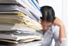 Stack of paperwork with overwhelmed lady