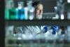 A man behind a shelf of chemicals recording data