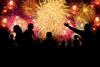 A photograph of a crowd of people watching a fireworks display