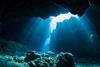 A photograph showing a ray of sunlight in an underwater cave