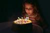 A picture of a little girl blowing candles on her birthday cake