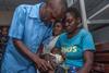 An image showing a health surveillance assistant giving a malaria vaccine dose to a toddler