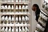 A woman at the Plastic exhibition looking at a shelf filled with rows and rows of plastic bottles