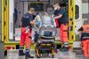 A photo of emergency staff with an isolation pod and an ambulance