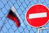 Access denied flag in front of fence with Russian flag blurred in the background behind the fence