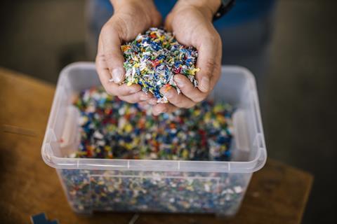 Man with container holding recycled plastic in factory