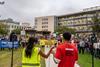 A photo of two young university workers shot from the back. They are standing on a stage, addressing a large crowd holding signs and placards with trade union logos