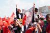 A crowd at a political rally in Turkey waving Turkish flags and a banner with the face of President Erdogan