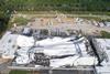 Aerial image of a large white warehouse that has been flattened surrounded by debris and upturned containers