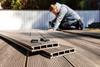 A man constructing a garden decking area using planks made of a composite materia