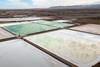 An overhead view of large green and white square salty pools in a desert environment